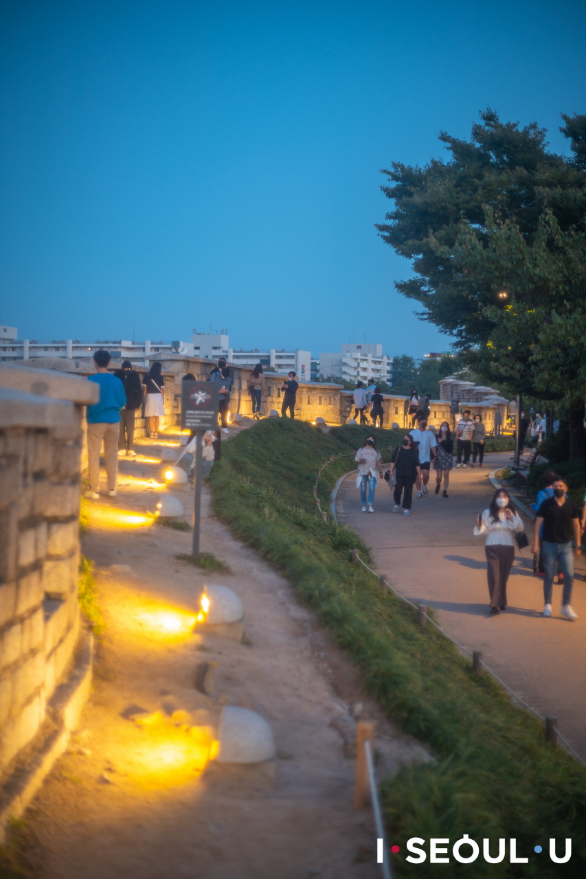 夕方にも明るく輝くナクサン(駱山)公園城郭道を歩く人々