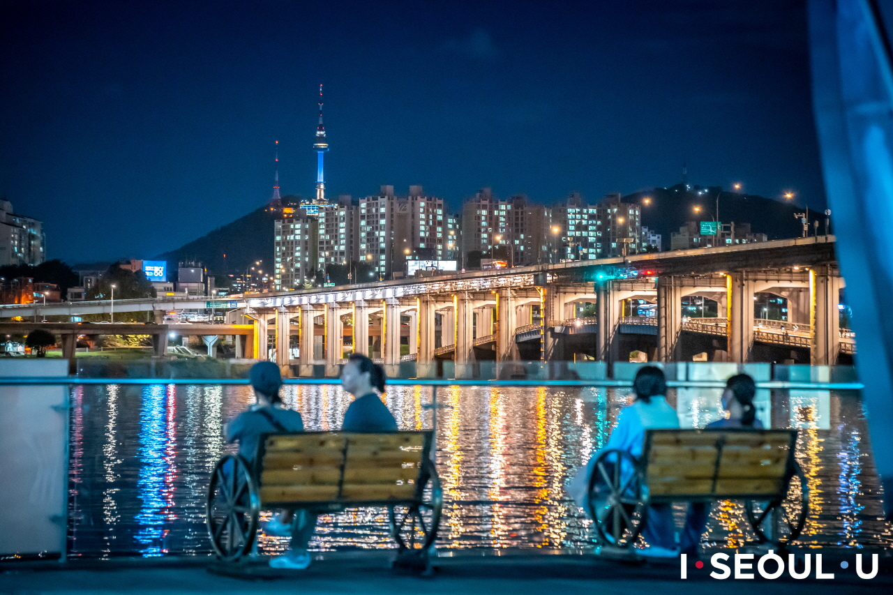 セビッ島のベンチに座ってハンガン(漢江)の夜景を眺める人々