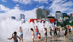 市役所前広場の噴水で水遊びをする夏の風景写真