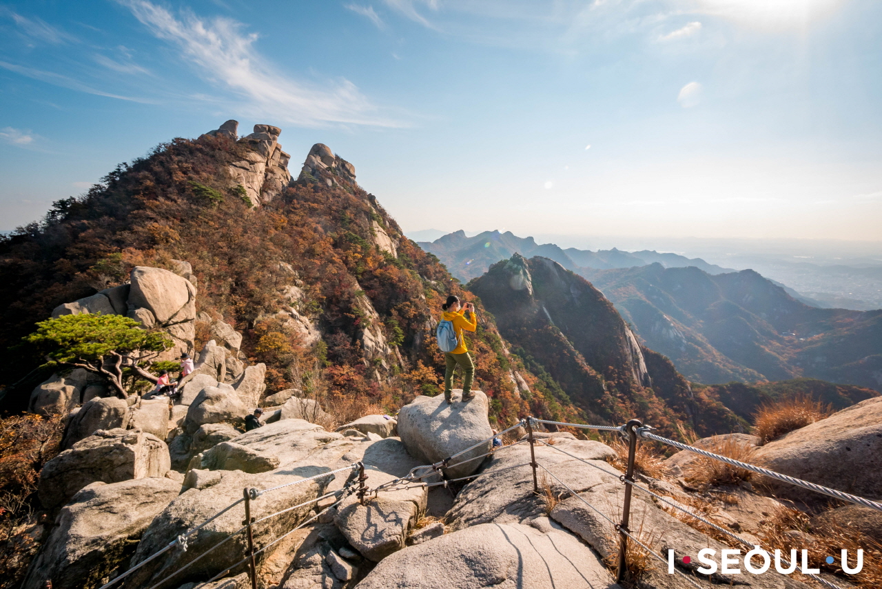 プッカンサン(北漢山)の頂上で景色の写真を撮っている女性